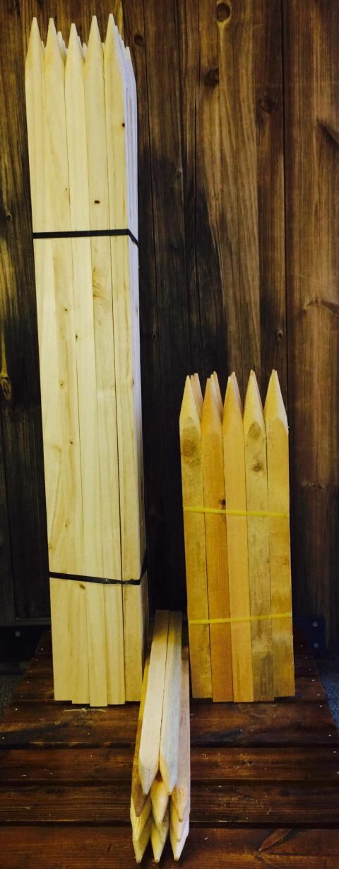 Pointed wood stakes posed against a dark wood backdrop.