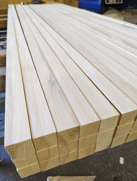 Freshly milled wood stakes lined up on the shop floor.
