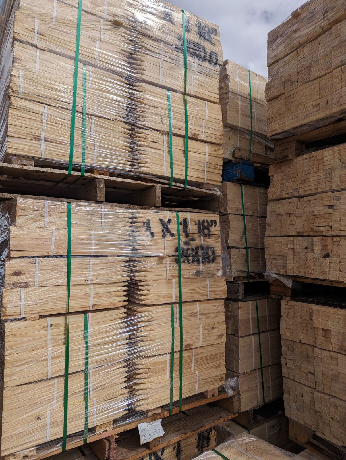 Wrapped pallets of pointed wood stakes staged in the Basic Industries yard, ready to ship.